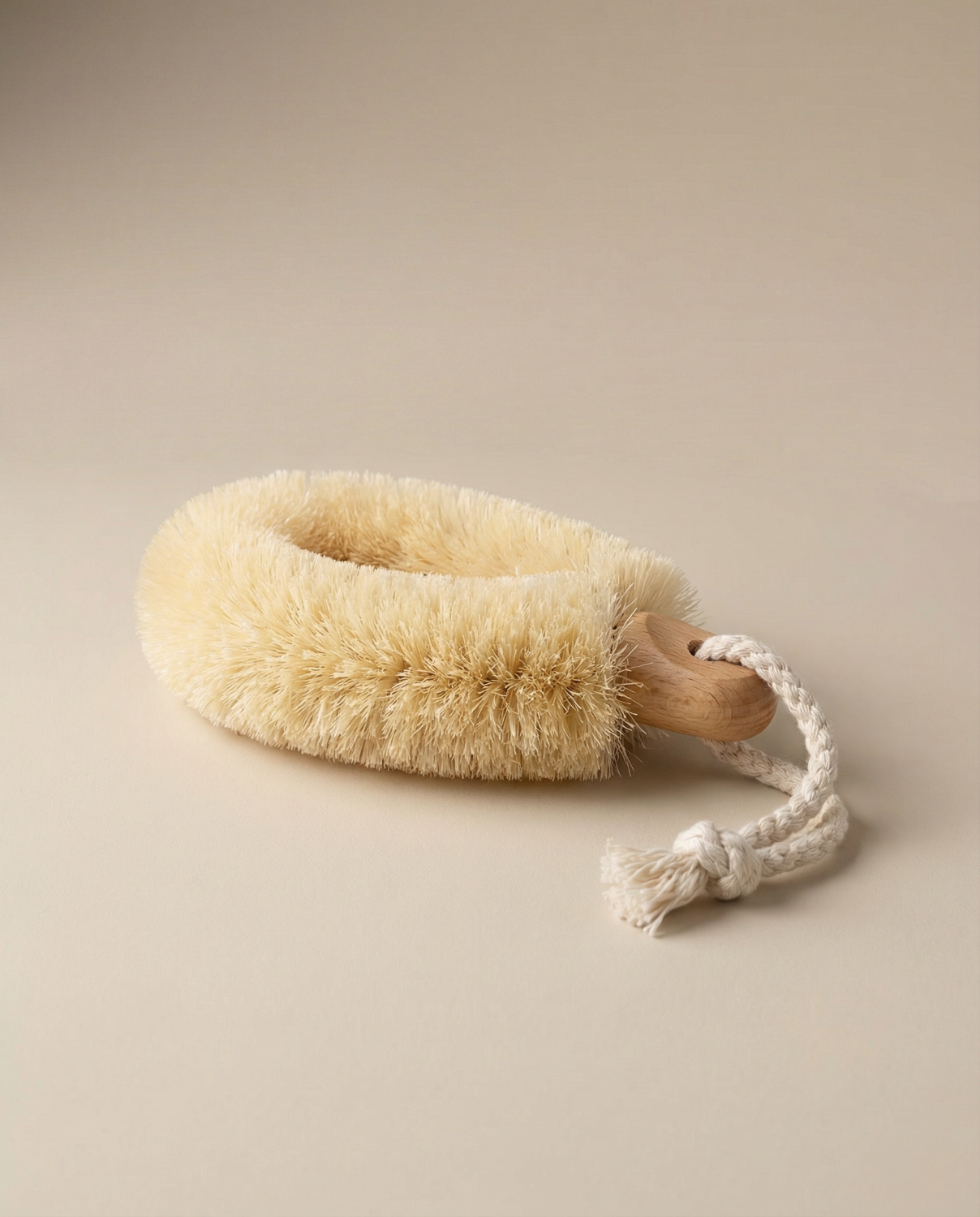 Natural fiber dry brush with wooden handle on a beige background