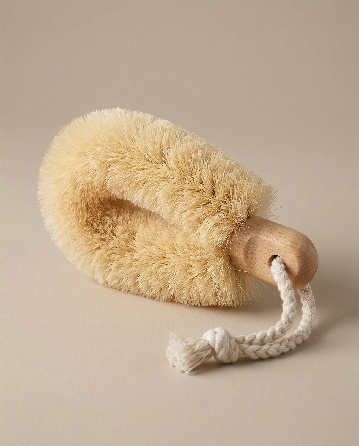 Body brush with wooden handle and natural bristles on a beige background