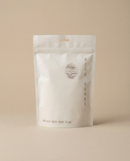White packaging of Ozco Goods Mineral Milk Bath Soak on a beige background