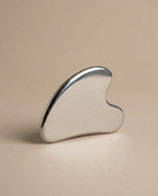 Ozco Goods Stainless Steel Gua Sha tool on a beige background